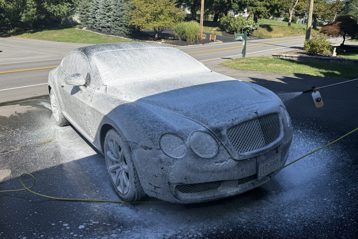 A Bentley Continental GT covered in snow foam during a mobile detail near Rochester NY