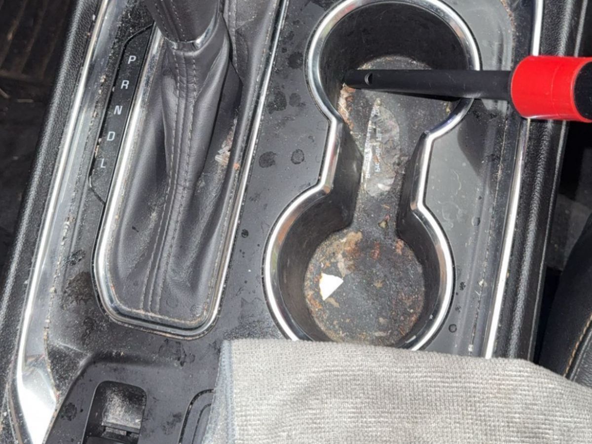 Chevrolet centre console before detailing, with debris and staining around the cupholders and shifter