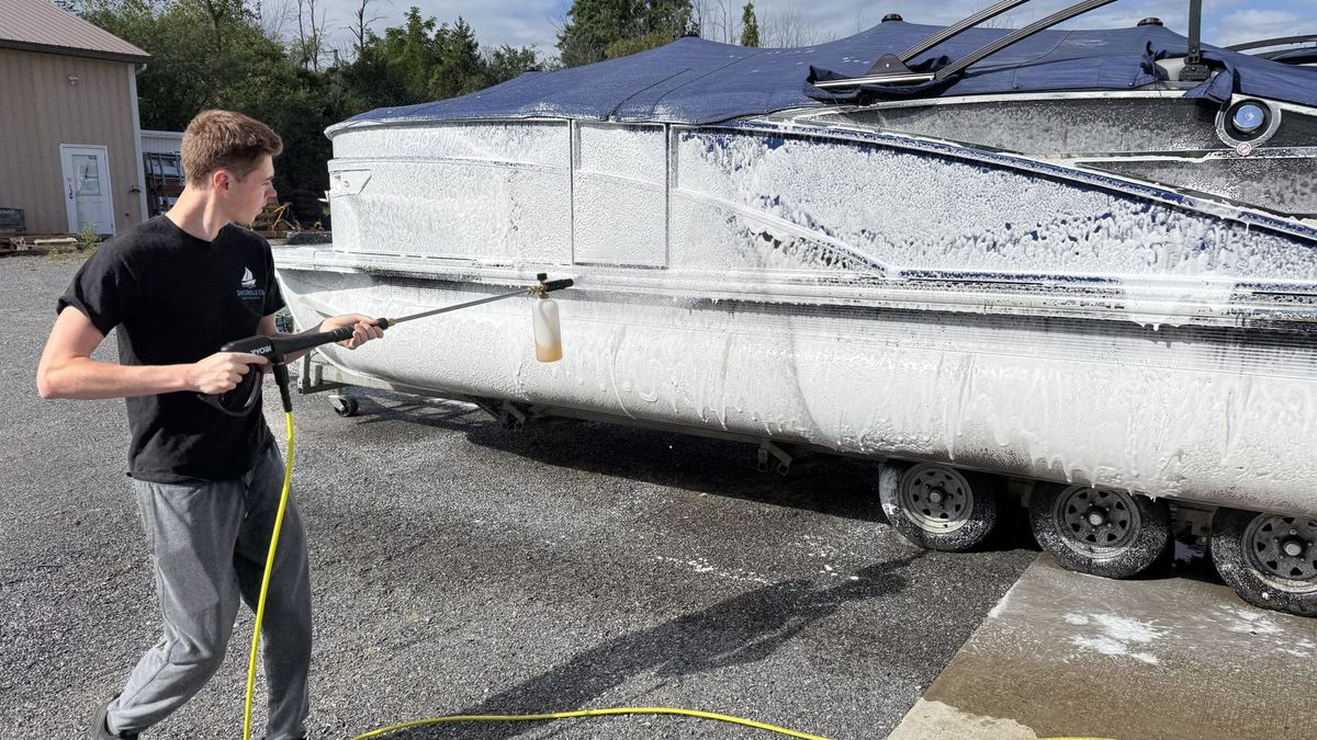 Shoreless Detailing technician applying snow foam to a pontoon boat on a trailer in the Finger Lakes